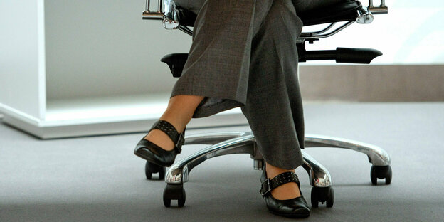 Beine einer Frau, die auf einem Bürostuhl sitzt
