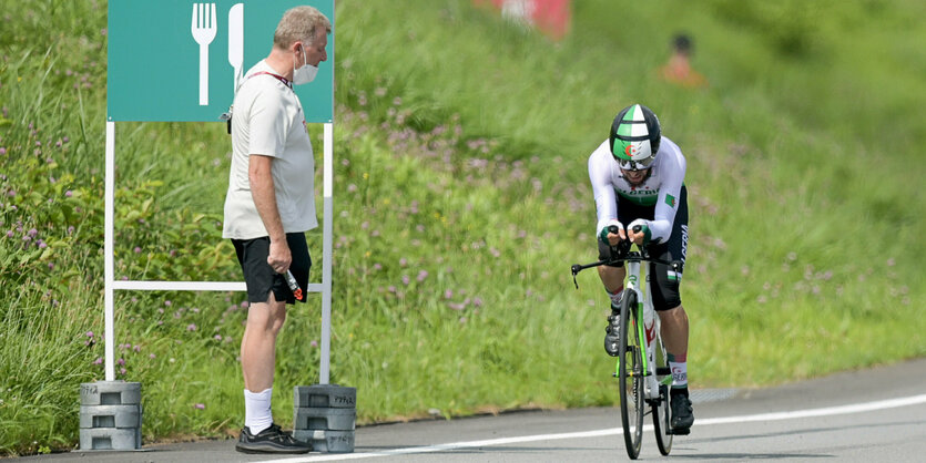 Radsportbetreuer Moseter steht am Straßenrand, Azzedine Lagab fährt vorbei