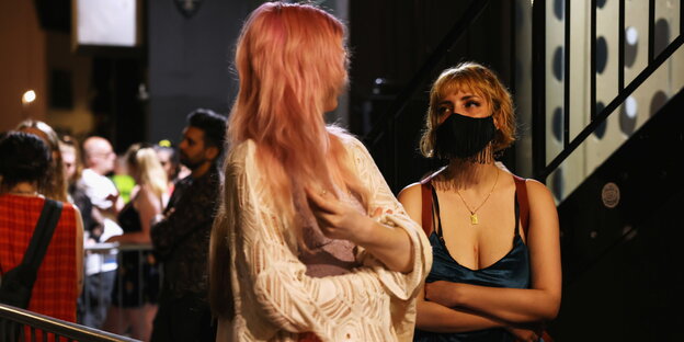 Frauen mit Gesichtsmasken am Eingang eines Nachtclubs