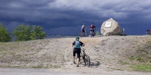 Radfahrer schieben einen Deich hoch: Und dann den Blick auf den Großräschener See genießen, der aus dem Tagebau Meuro entstand
