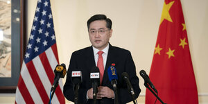 Qin Gang steht vor mehreren Mikrofonen. Hinter ihm die US-Flagge und die chinesische Flagge