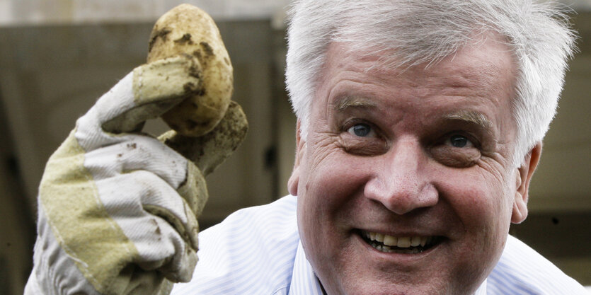 Horst Seehofer hält grinsend eine Kartoffel in die Kamera