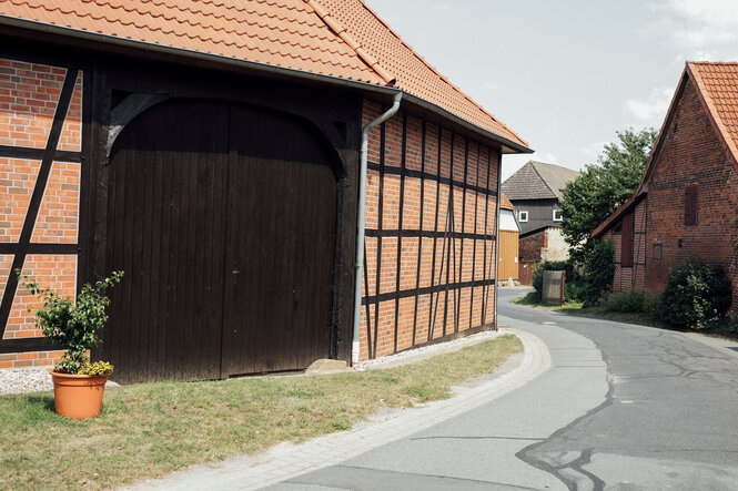 Eine Dorfstraße, im Vordergrund eine Fachwerkscheune