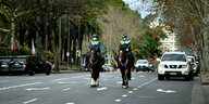 Zwei Polizisten auf Pferden reiten durch eine leere Straße