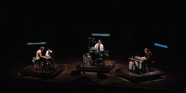 Das Trio Lange//Berweck//Lorenz auf einer verdunkelten Bühne an den Synthesizern, einzeln angeleuchtet