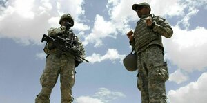 Ein US-Soldat und Dolmetscher gekleidet in Tarnmuster kommuniziert über Funk