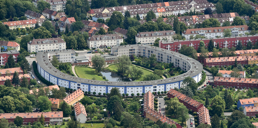 Die Hufeisensiedlung aus der Luft - eine grüne Wohnanlage. In der Mitte befindet sich ein hufeisenförmiges Gebäude