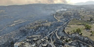 Eine Luftaufnahme zeigt verbrannten Wald und einen schwer beschädigten Ort