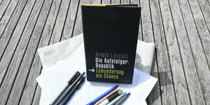 Das Buch "Aufsteigerrepublik" von Armin Laschet auf einem Holztisch mit Stiften