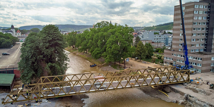 Ein Kran steht neben einer Brücke über einen Fluss