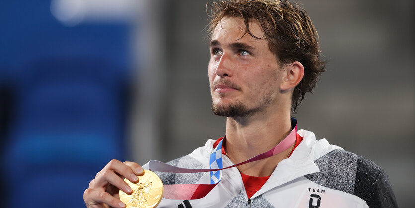 Alexander Zverev hält lächelnd die Goldmedaille in der rechten Hand