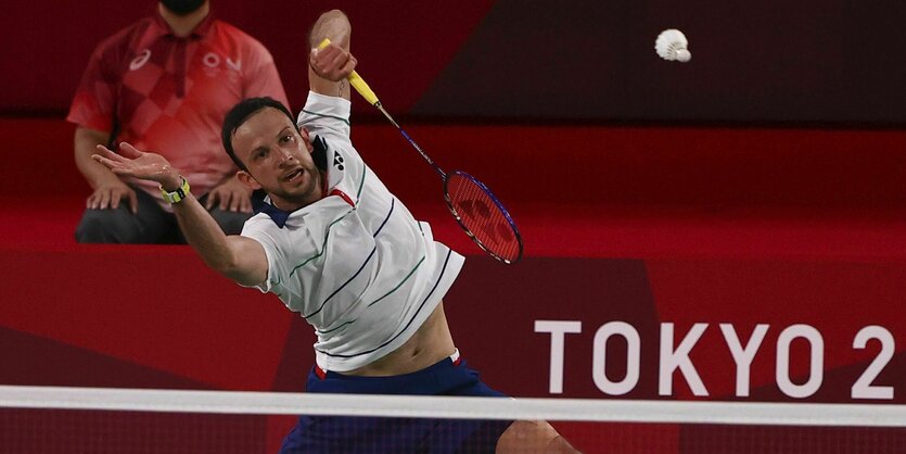 Ein Badmintonspieler macht Verrenkungen, um den Badmintonball zu bekommenrrenkungen zu machen