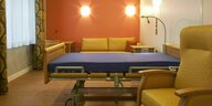 Ein Krankenhausbett steht in einem hell und in ruhigen Farben gestaltenden Raum, der bequeme Sitzmöglichkeiten für Angehörige bietet
