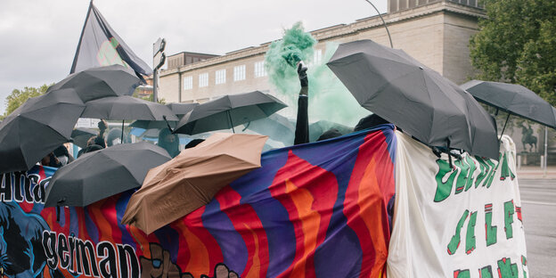 Ein Demonstrationsblock mit Regenschirmen und Transparenten an der Seite dteht vor der Hamburger Kunsthalle