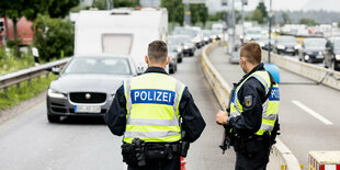 Zwei Polizisten kontrollieren an einer Autobahn