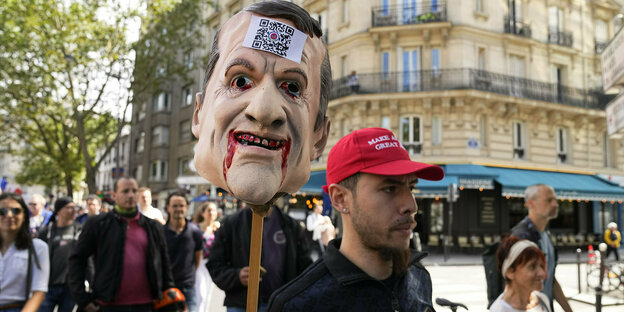 Ein Demonstrant in Paris hält den Puppenkopf von Präsident Macron, dem Blut aus dem Mund fließt