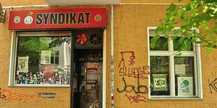 Eine gelbe Hauswand, darin ein Schaufenster und eine Kneipentür. Darüber das rote Schild 'Syndikat'