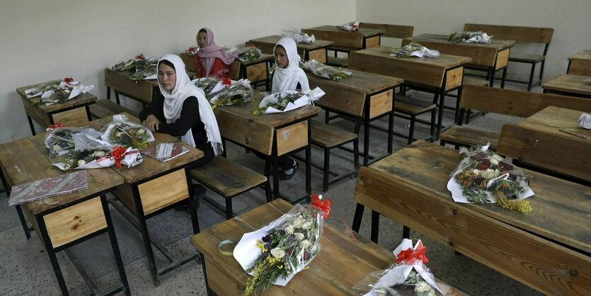 Trauersträusse liegen auf leere Schultischen, nur 3 Mädchen in der Klasse sind noch da