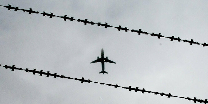 Die Silhouette eines Flugzeugs zwischen Stacheldraht