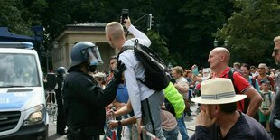 Ein Mann stellt sich auf der verbotenen Querdenkerdemonstration auf der Straße des 17. Juni an der Siegessäule auf ein Polizeigitter