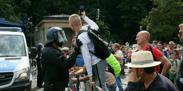 Ein Mann stellt sich auf der verbotenen Querdenkerdemonstration auf der Straße des 17. Juni an der Siegessäule auf ein Polizeigitter
