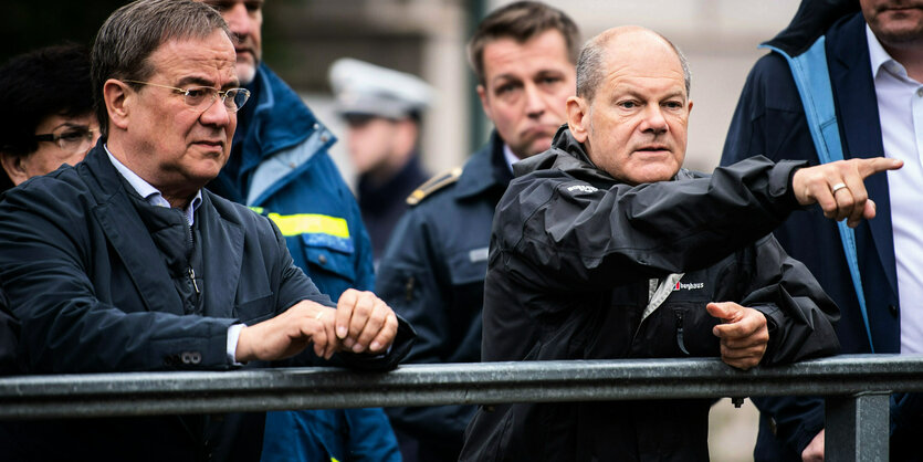 Laschet und Scholz stehen mit anderen Personen auf einer Brücke.