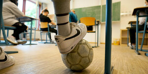 Blick in ein Klassenzimmer, Fuß mit Fußball im Vordergrund.