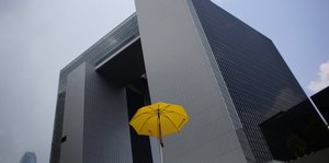 Ein gelber Regenschirm vor einem Hochhaus