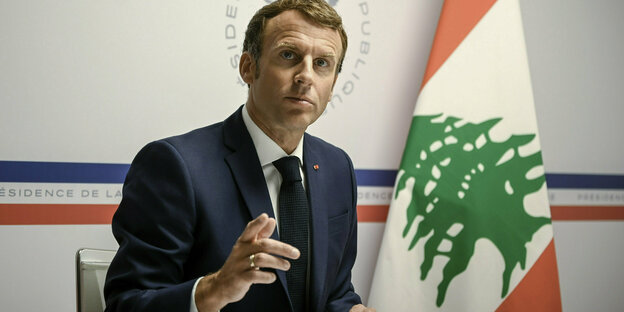 Der französische President Macron vor einer Flagge des Libanon.