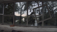 Ein Fenster hängt lose in einer Fensterfront, dahinter ist ein See mit Bäumen