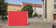 Ein rote Plakatwand steht auf einem Platz