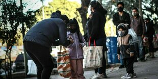 Eine Frau mit zwei Kindern steht in einer Schlange und wartet