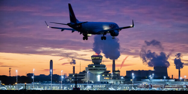 Der Berliner Flughafen Tegel in der Abenddämmerung, im Vordergrund landet ein Flugzeug.