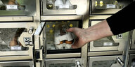 Ein Hand greift in ein Fach eines Eierautomaten.