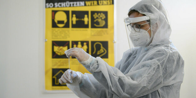 Eine Mitarbeiterin im weißen Overall und mit Schutzmaske in einem Corona-Testzentrum