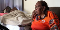 Eine ältere Frau sitzt vor einem Krankenbett