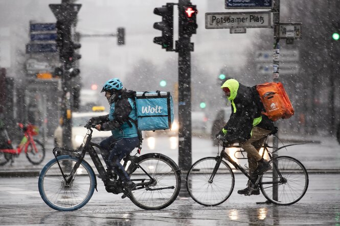 Zwei Rider von zwei unterschiedlichen Lieferdiensten sind im Schneeregen unterwegs