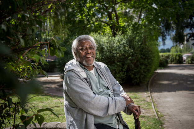 Myaka Sururu Mboro sitzt auf einer Bank in einem Park für ein Porträt: der Aktivist ist Mitbegründer des Vereins Berlin Postkolonial