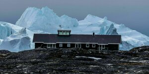 Eisberg hinter einem Haus auf Grönland