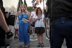 Zwie Frauen betend ohne Schutzmasken vor Polizisten Zwie Frauen betend ohne Schutzmasken vor Polizisten