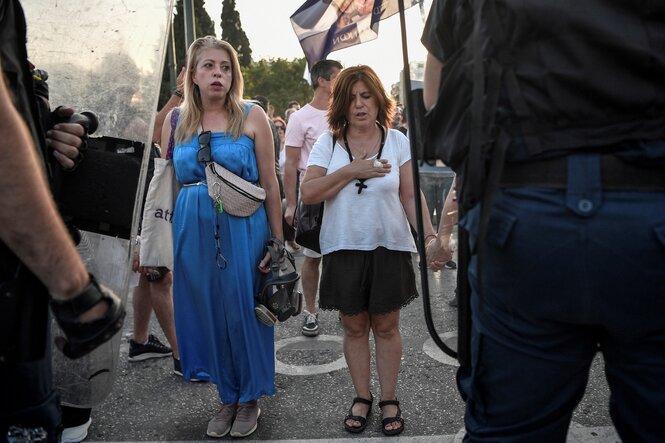 Zwie Frauen betend ohne Schutzmasken vor Polizisten