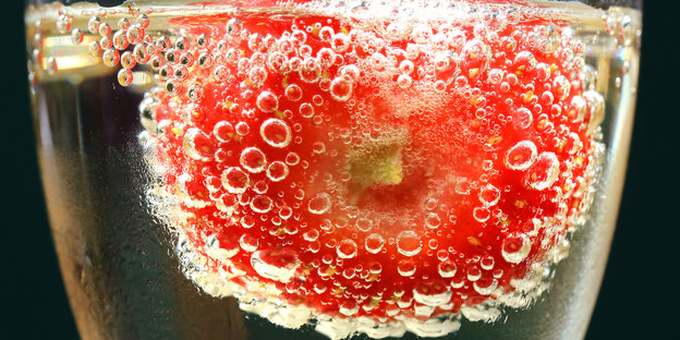 Wasserblasen bilden sich an einer roten Frucht in einem Glas