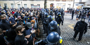 Viele Menschen stehen auf der Straße mit Kopfsteinpflaster vor einer Polizeiabsperrung