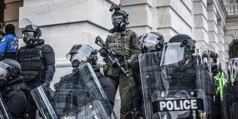 Polizisten mit Schildern und Gasmasken stehen auf Treppen