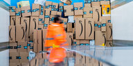 Ein Amazon-Mitarbeiter vor einem Berg von Paketen