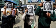Drei Demonstranten mit Schildern, die das Gesicht von Juan Sandoval zeigen