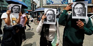 Drei Demonstranten mit Schildern, die das Gesicht von Juan Sandoval zeigen