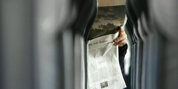 Ein Mann liest eine Zeitung in der Bahn