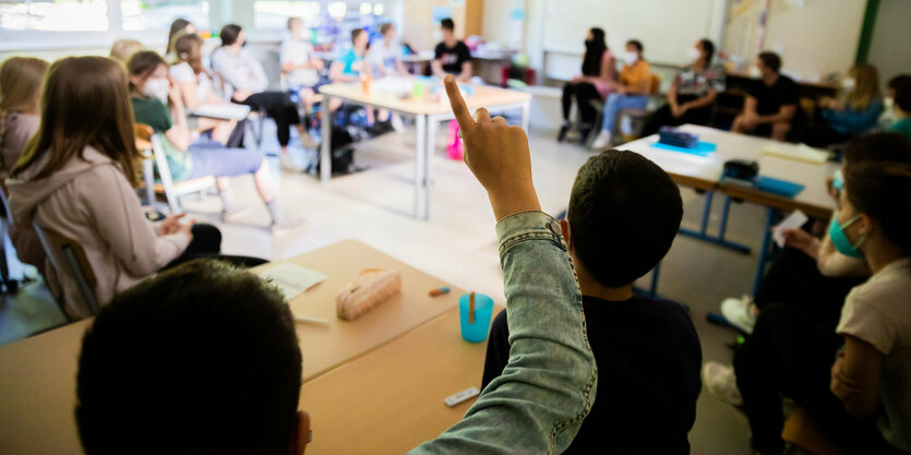 Schüler sitzen im Kreis im Klassenzimmer, ein Schüler meldet sich