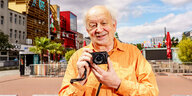 Der Fotograf Günter Zint hält einen Fotoapparat in der Hand
